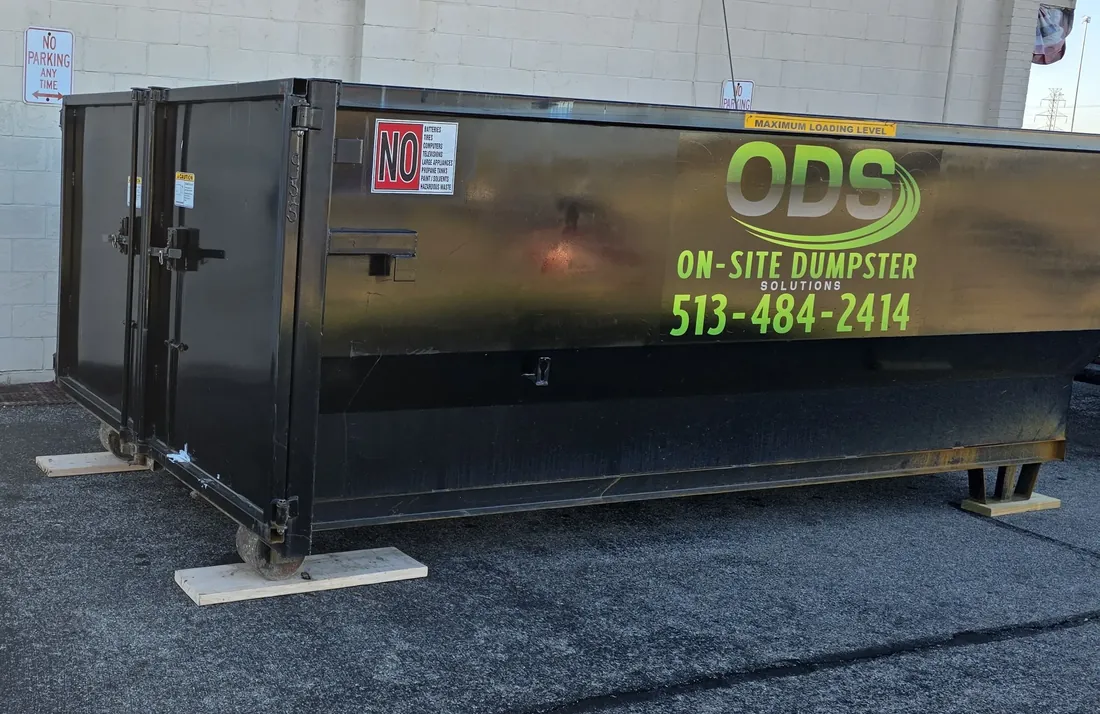 On-Site Dumpster Solutions roll-off container resting safely on protective wood blocks.
